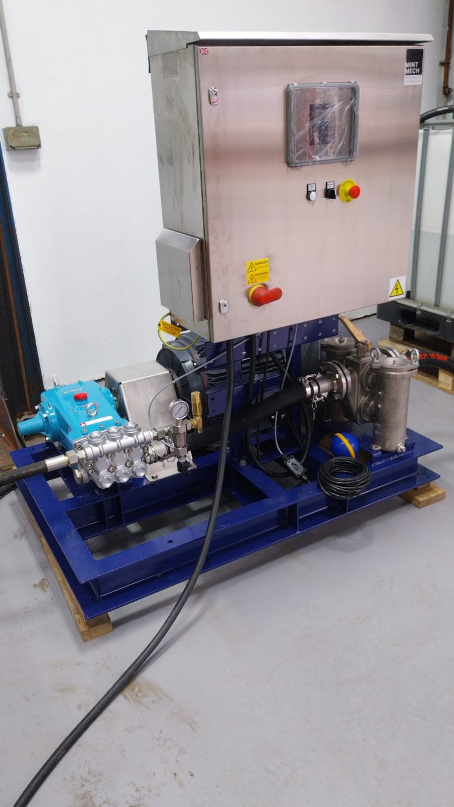 Electric pumping skid with a stainless steel control cabinet on a blue frame