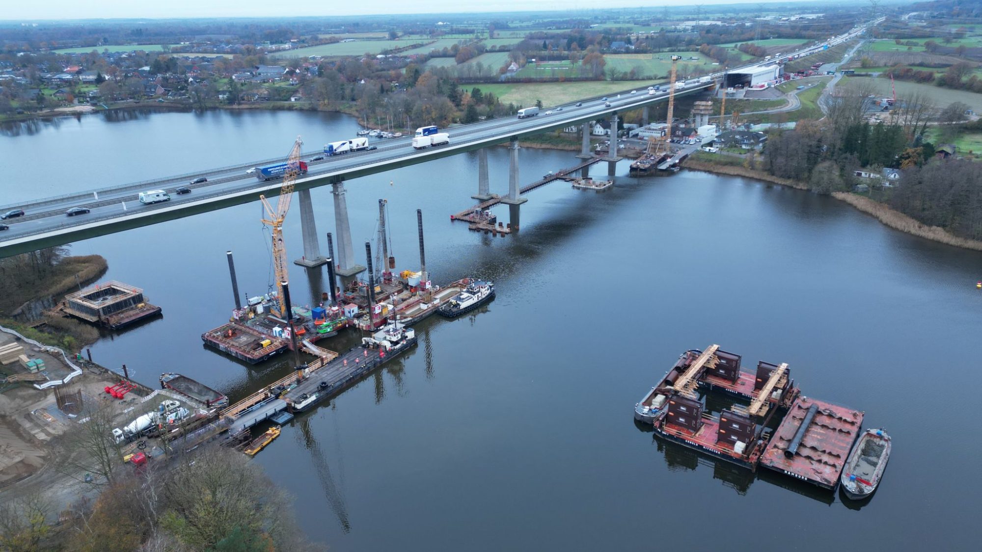 Aerial view of barges and pontoons moored beside a road bridge under construction