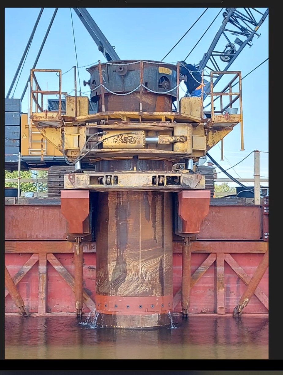 Large drilling unit mounted over a steel casing on the side of a barge