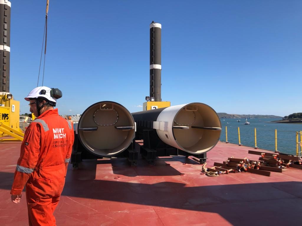 MintMech engineer on a barge deck beside large steel pile sections