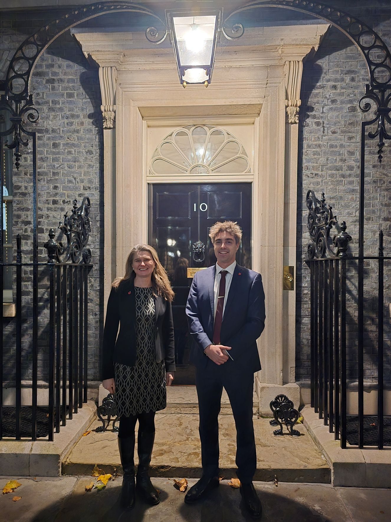 Two people standing outside the door of 10 Downing Street