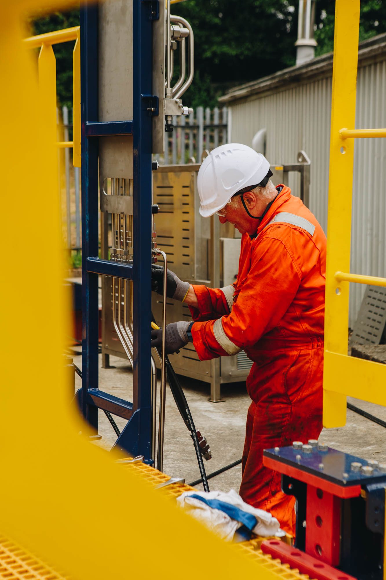 Engineer in a hard hat adjusting equipment beside yellow handrails