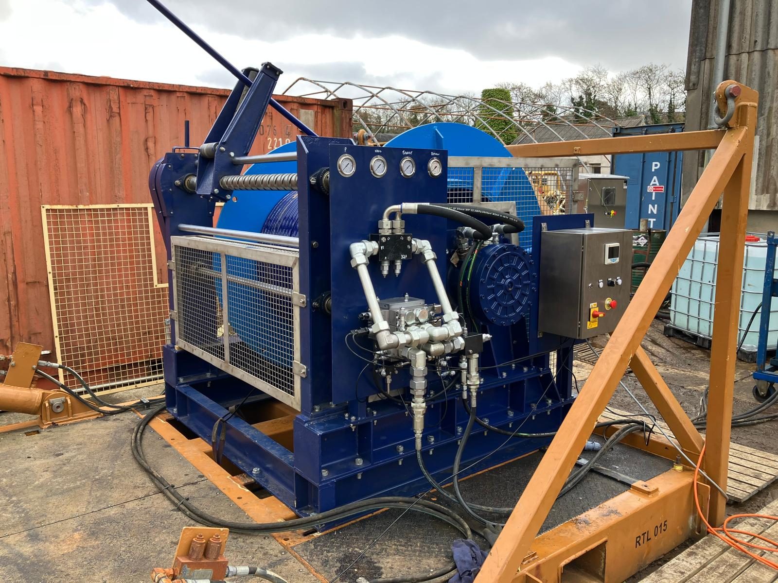 Blue hydraulic reeler with a spooling drum inside an orange transport frame