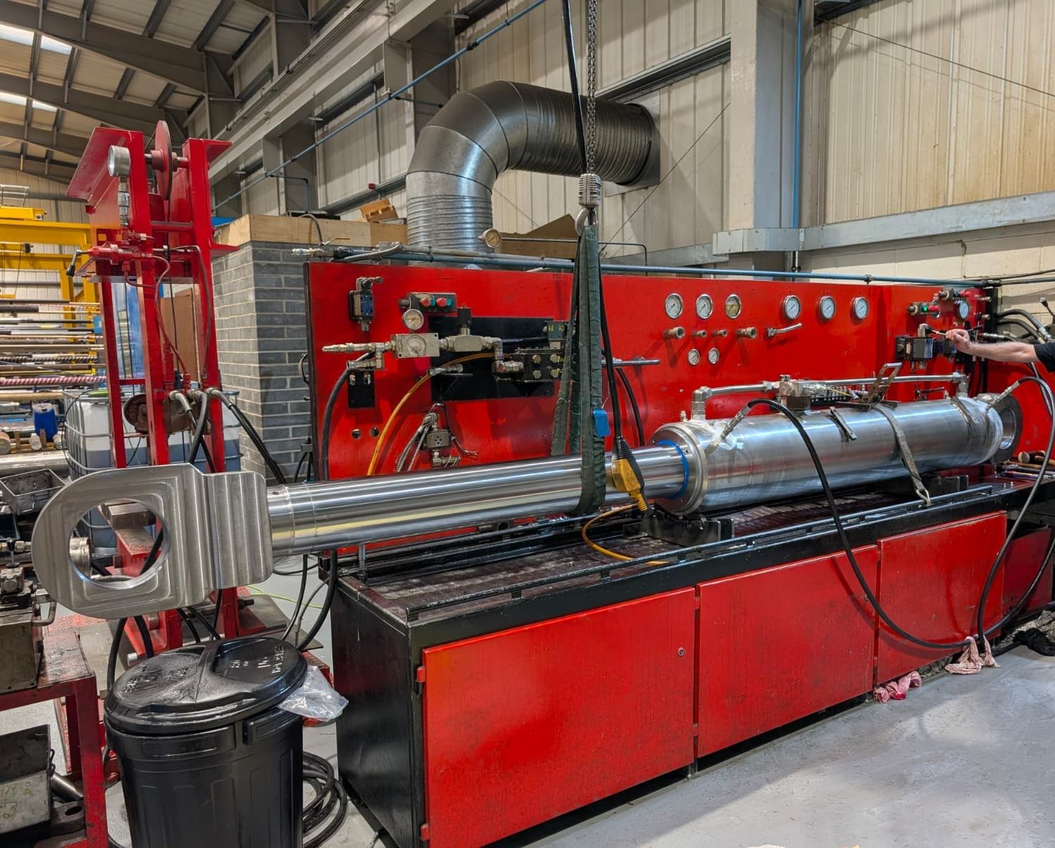 Large hydraulic cylinder on a red test bench in a workshop