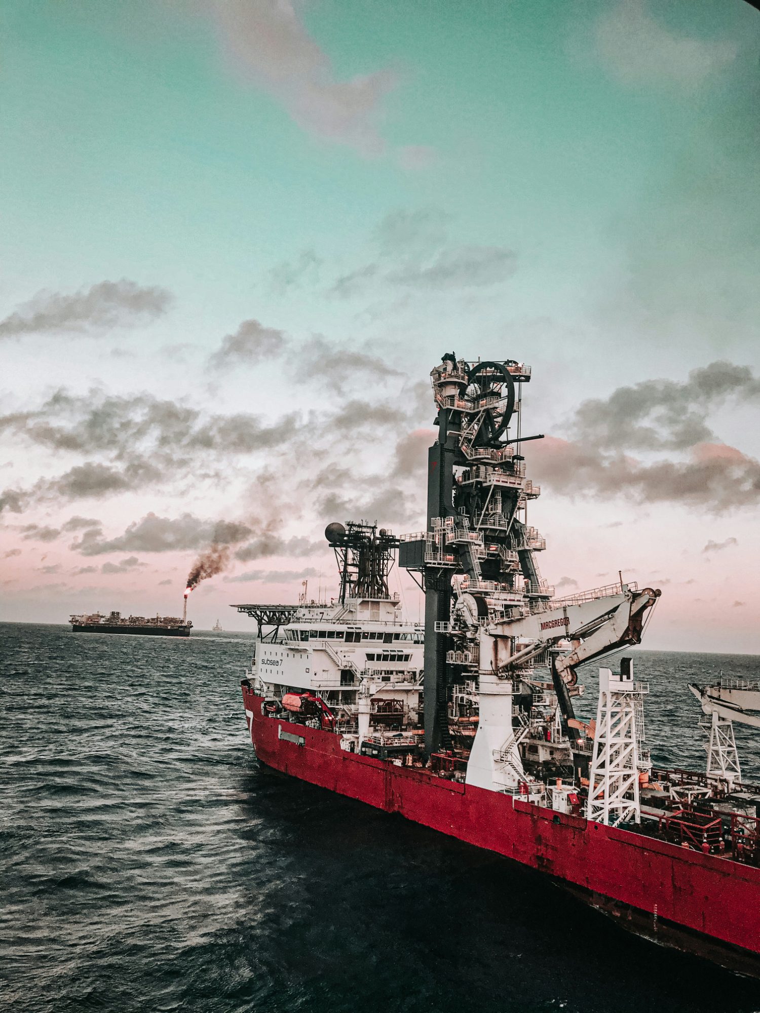 Offshore construction vessel with a tall lay tower at sea at dusk