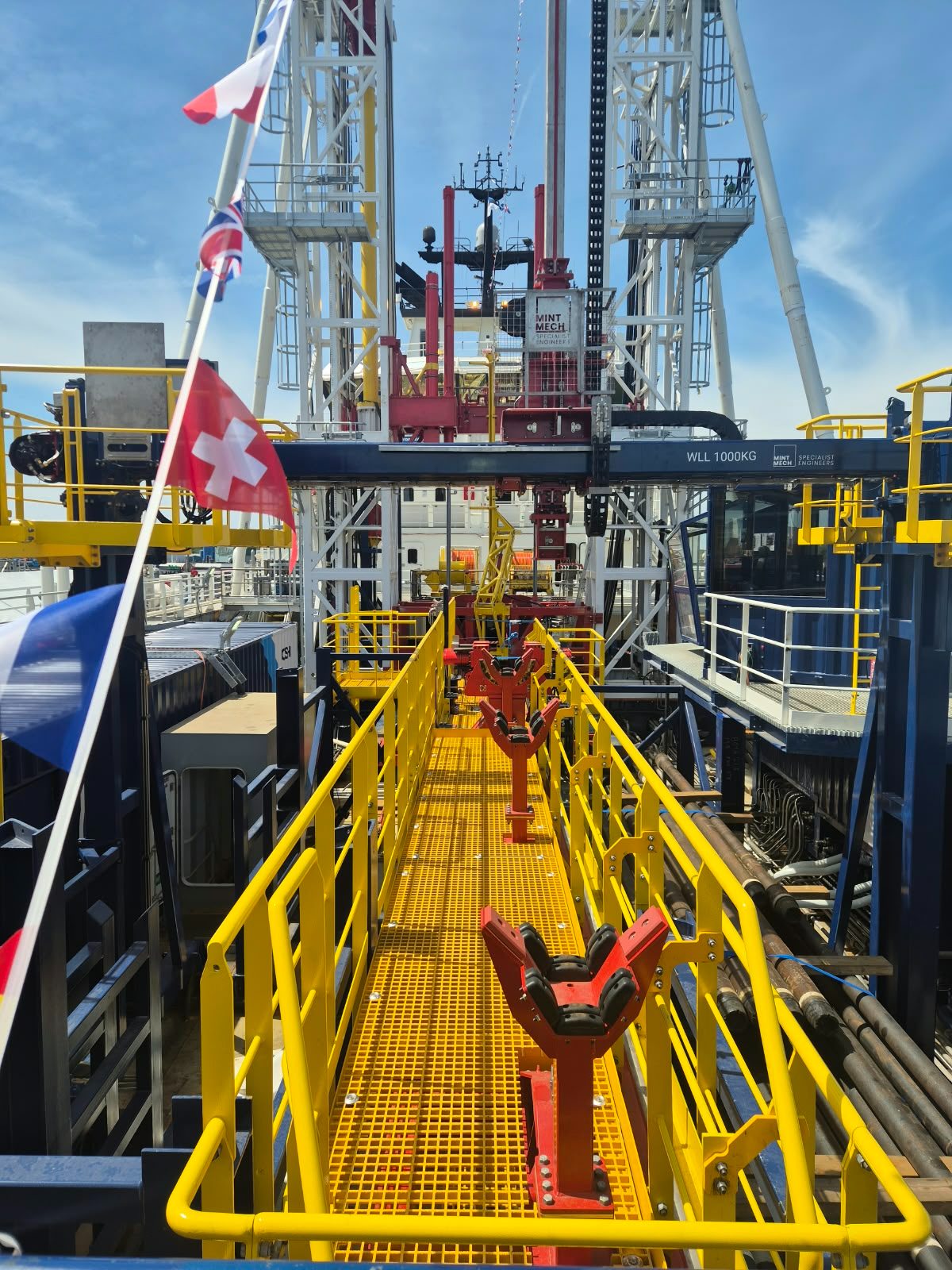 Pipe handling system with red rollers along a yellow walkway on a drilling vessel