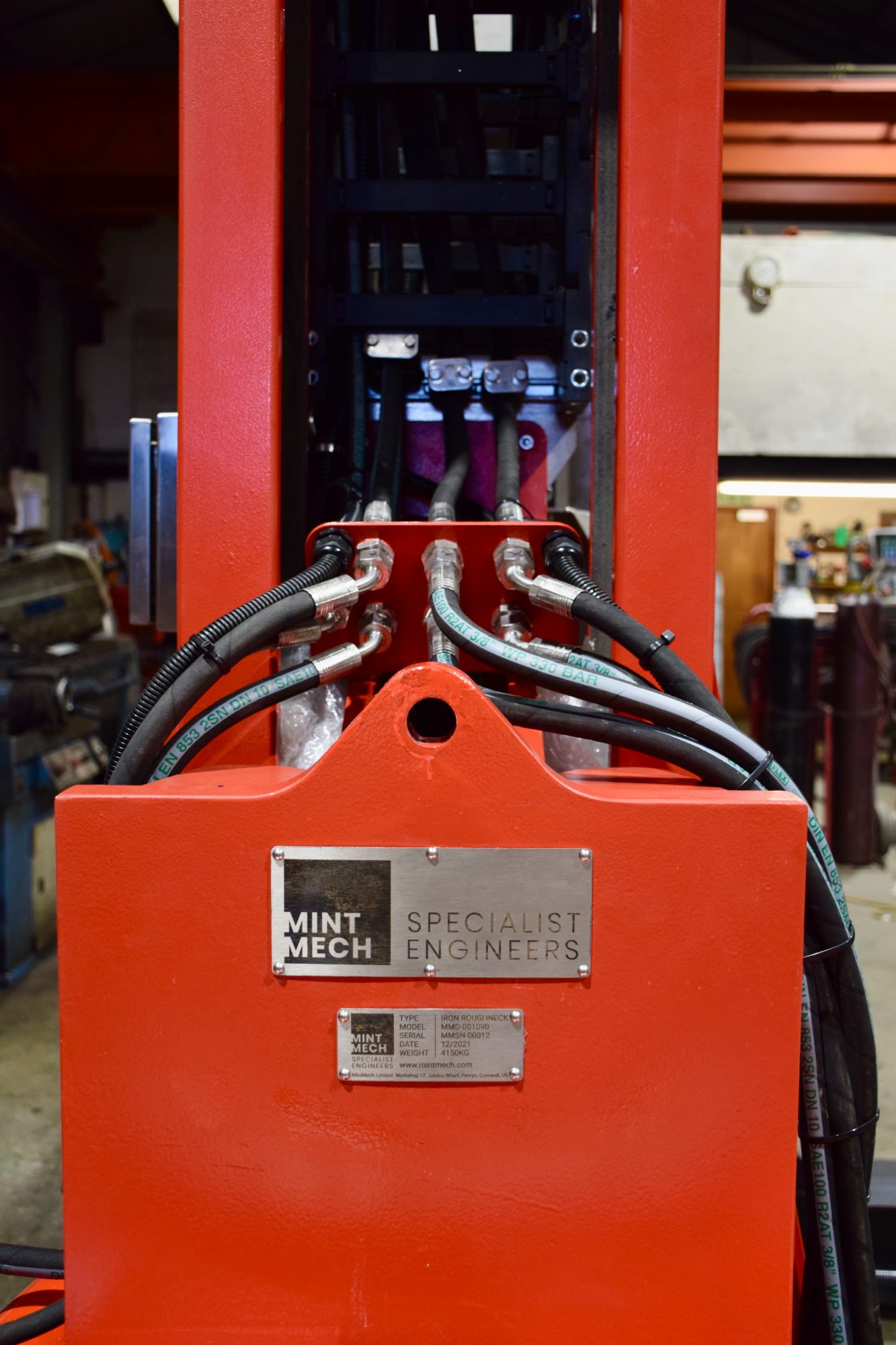 Red equipment frame with hydraulic hoses and a MintMech nameplate