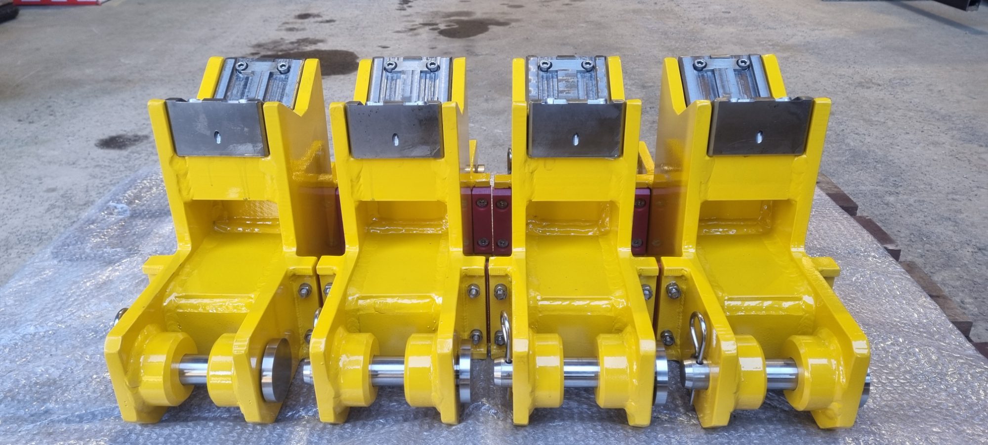 Row of four yellow clamp assemblies laid out on a workshop floor