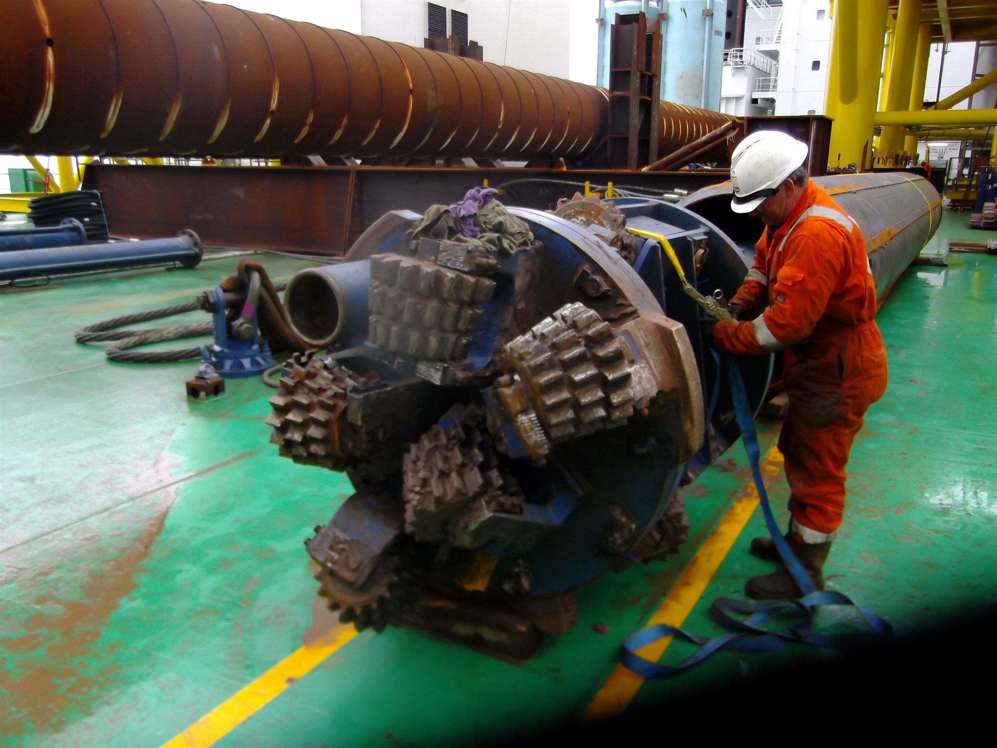 Large-diameter drill bit on deck with an engineer alongside