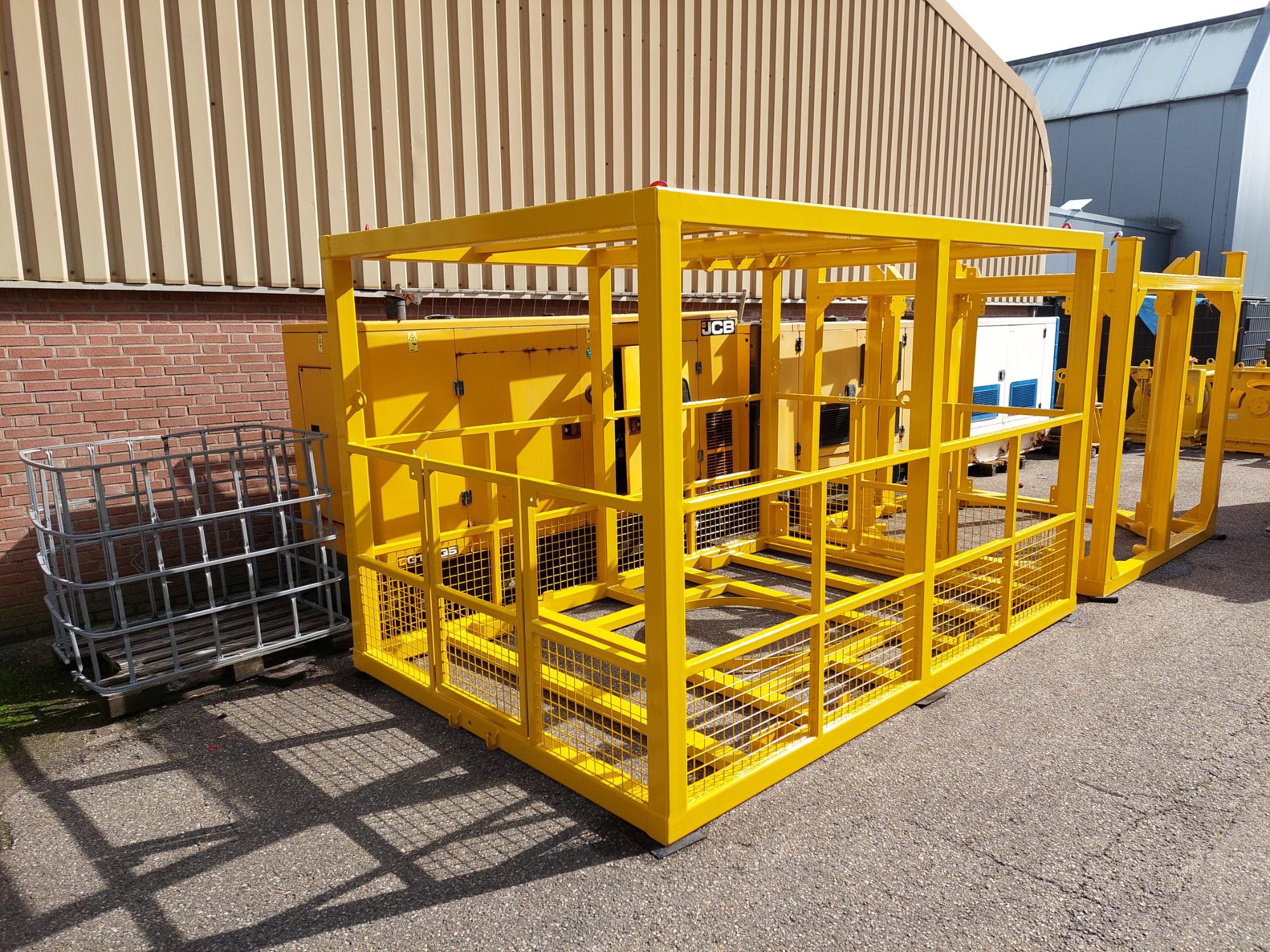 Yellow fabricated steel frames with mesh panels standing in a yard