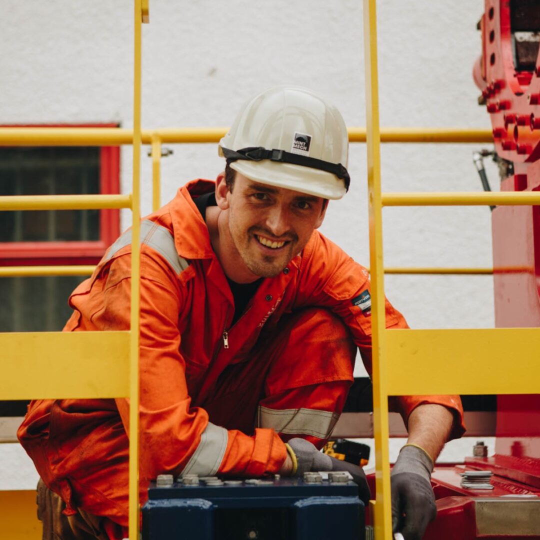A male specialist engineer pauses work to look up at the camera and smile