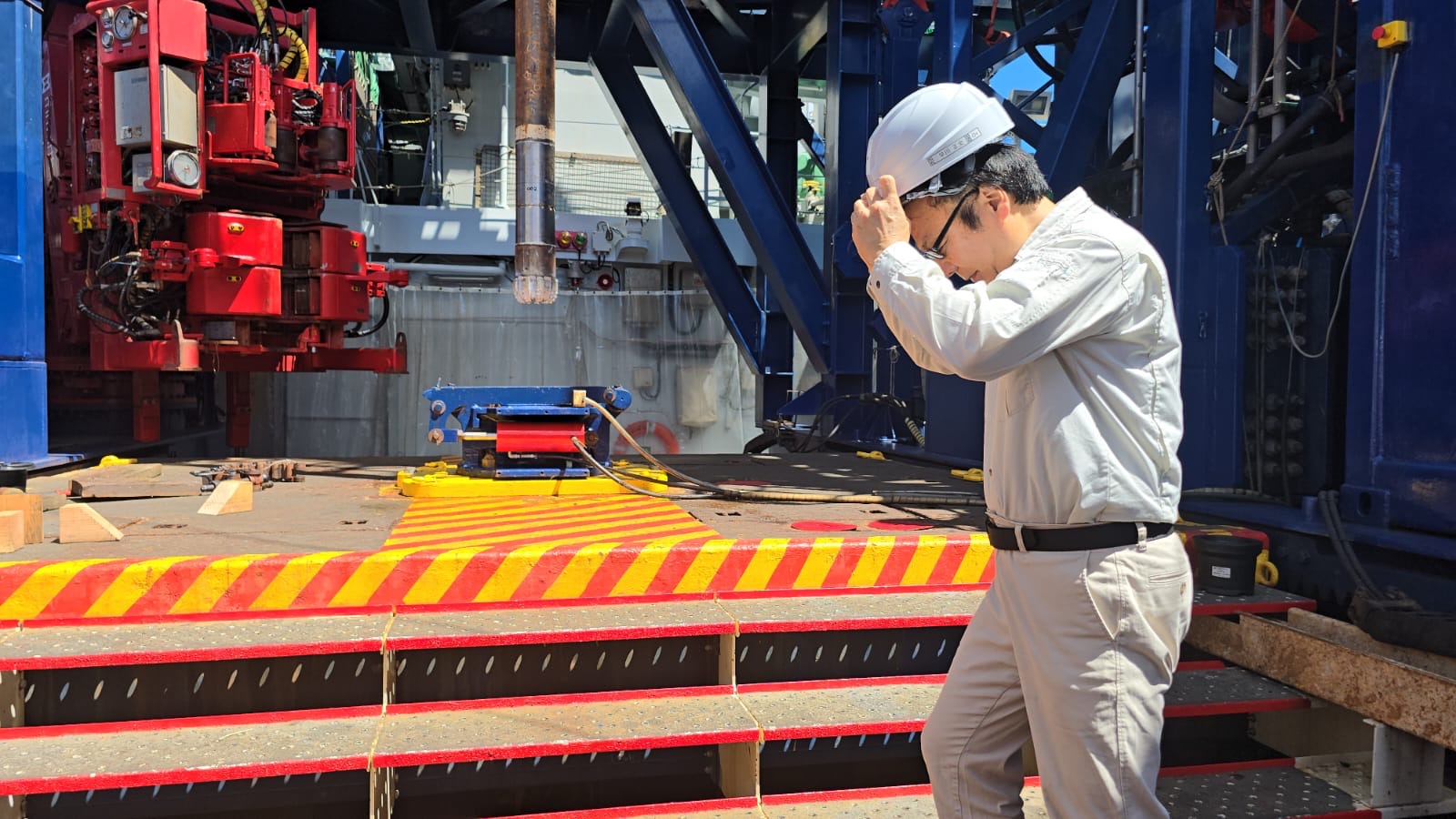 An engineer wearing a helmet walking from one side of a vessel fitted with a MintMech deck spread to the other