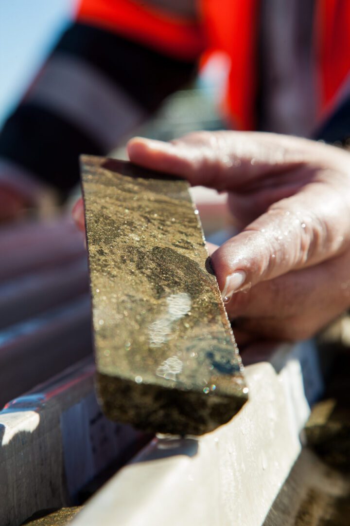 A hand holding a cylindrical core sample of rock